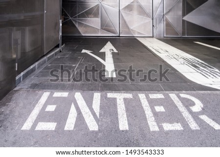 Enter text with two arrows painted on the floor of an underground parking entrance