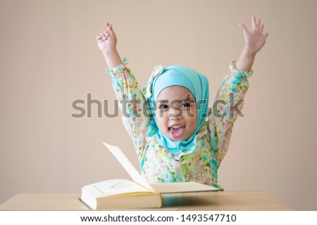 Muslim kid raised up hands for celebration after school time and finishing the class. Education concept. Royalty-Free Stock Photo #1493547710
