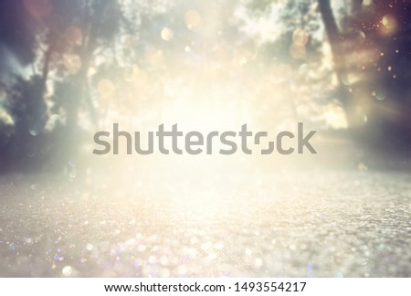 Abstract background of light burst among trees and glitter golden bokeh lights