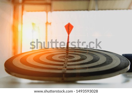 Red dart arrow hitting in the target center of dartboard on bullseye with sun light vintage style, Target marketing and business success concept.