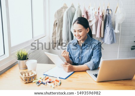 Entrepreneurs small business owner,Asian women Fashion designer drawing new sketches collection,sent a business e-mail to client.sales success,working using laptop,digital smartphone in workshop