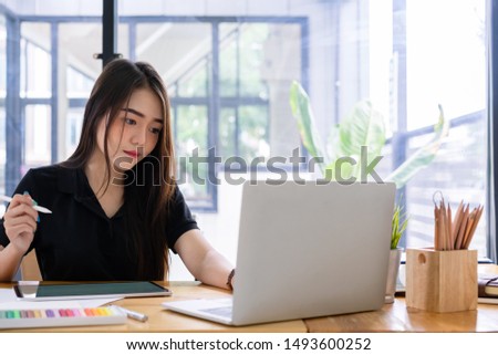 Beautiful young asian freelance graphic designer hand working with stylus pen and laptop computer for creative design project.
