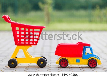 Bright plastic colorful toys for children outdoors on sunny summer day. Car truck and shopping pushcart.