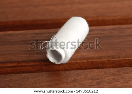 white sewing thread on wooden background