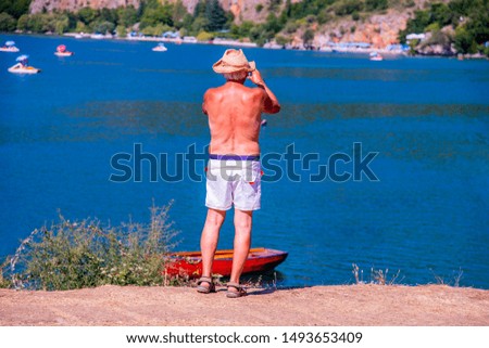 Back view of older man take a photo at the beautiful view at the lake.