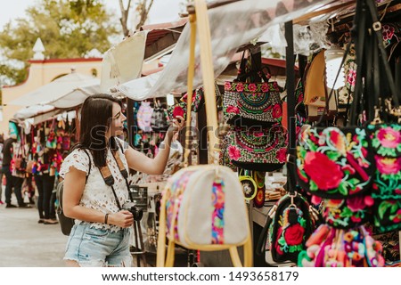 traveler girl buying souvenirs in the traditional Mexican market in Mexico streets, hispanic tourists standing in outdoor Royalty-Free Stock Photo #1493658179