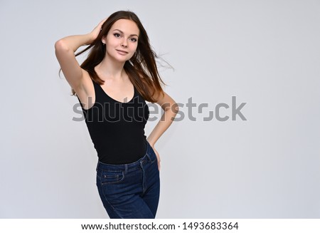 Portrait of a cute brunette girl with beautiful curly hair in a black T-shirt on a white background. Smiling, talking with emotions.
