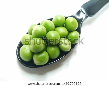 A picture of fresh green peas on black spoon