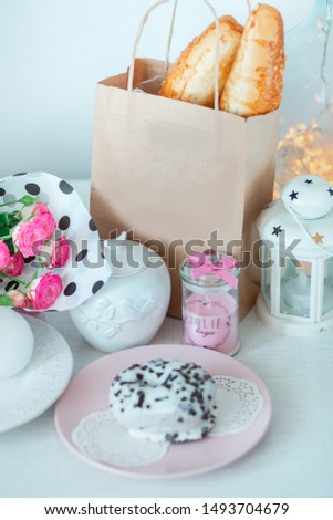 Strawberry dessert on a white table with spray roses and a burning candle. On the flask of the candle is an inscription in French: "Beautiful candle"
