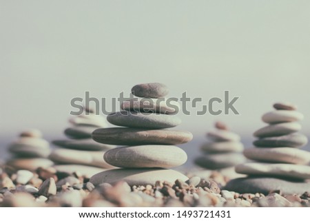 Zen pyramid of spa stones on the blurred sea background. Sand on a beach. Sea shores. Place for text.	