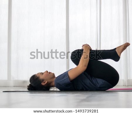 Beautiful asian young woman wearing sportswear practicing yoga in studio,natural light.Concept : yoga poses for beginner.