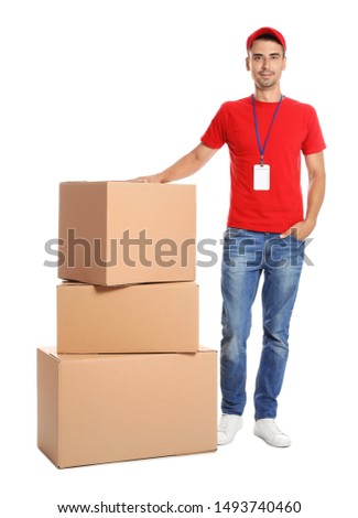 Young happy courier near pile of cardboard boxes on white background