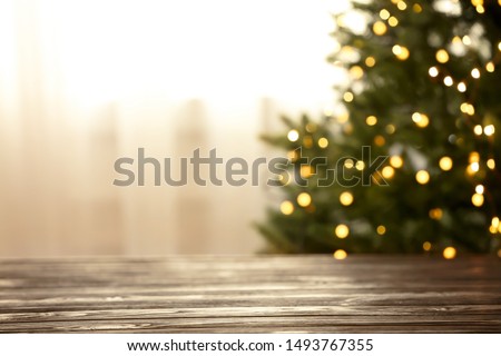 Empty table and blurred fir tree with yellow Christmas lights on background, bokeh effect. Space for design Royalty-Free Stock Photo #1493767355