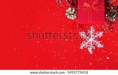 Decorative white snowflake, red present box, golden cones and shiny derative balls as a festive holiday background.