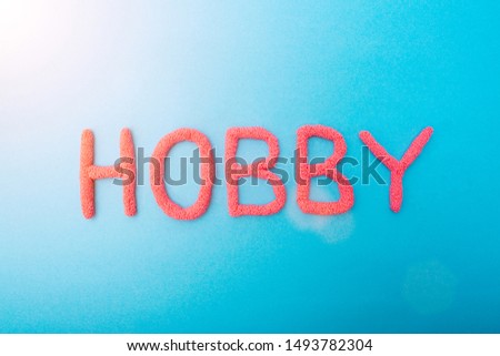 Red plasticine hobby lettering on blue background, hobbies concept, inscription