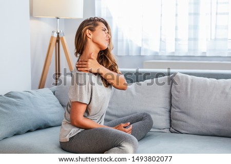Pain in the shoulder. Upper arm pain, People with body-muscles problem, Healthcare And Medicine concept. Attractive woman sitting on the bed and holding painful shoulder with another hand. Royalty-Free Stock Photo #1493802077