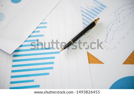 Many charts and graphs with magnifying glass and many pencil. Re