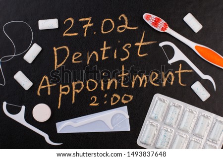Dentist appointment reminder on chalkboard. Toothbrush, dental floss toothpick, chewing gums and inscription Dentist Appointment. Dental care concept.