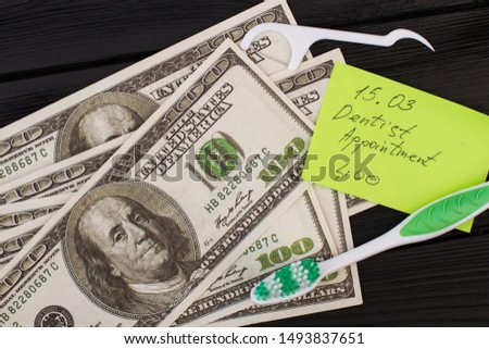 Note dentist appointment, toothbrush and money. American dollars, toothbrush and paper card with inscription Dentist Appointment.