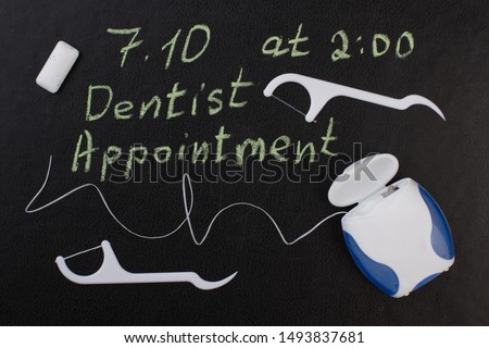 Note dentist appointment and dental floss. Reminder dentist appointment on chalkboard and dental care products.