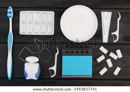 Dental health concept. Toothbrush, dental floss, cleaning powder and blank planner on woden background.