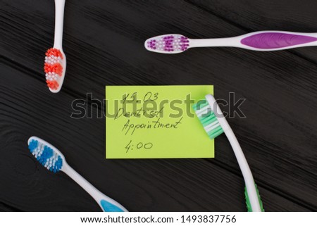 Colorful toothbrushes and card with inscription Dentist Appointment. Message with date and toothbrush to remind dentist appointment.
