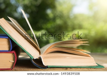 Open book on a wooden table in a garden, sunny summer day, reading in a vacation concept