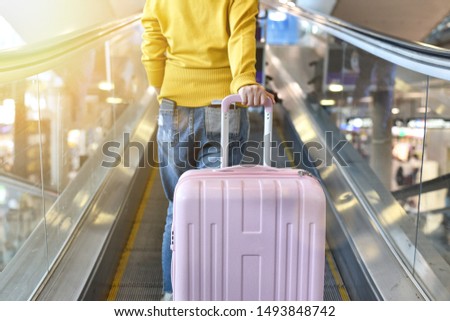 Traveler carry big suitcase on escalator walkway at the airport terminal, Passenger walking with luggage to departure check-in counter, Tourist arrive at destination, Travel concept. Royalty-Free Stock Photo #1493848742