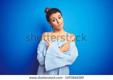 Young beautiful woman wearing bun hairstyle over blue isolated background Pointing to both sides with fingers, different direction disagree