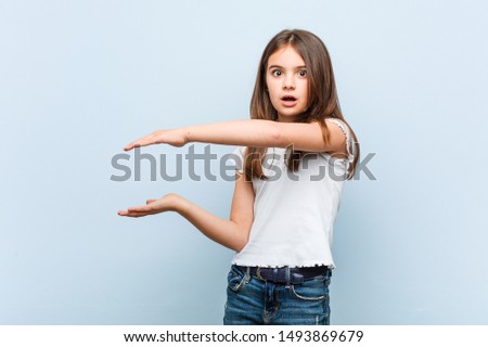 Cute girl shocked and amazed holding a copy space between hands.