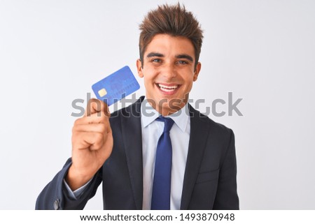 Young handsome businessman wearing suit holding credit card over isolated white background with a happy face standing and smiling with a confident smile showing teeth