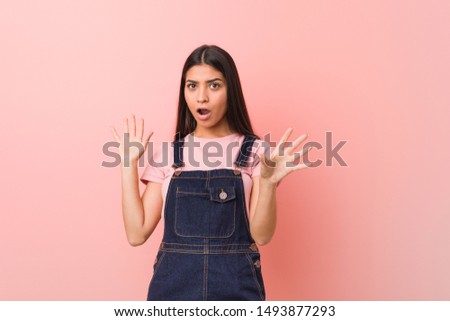 Young pretty arab woman wearing a jeans dungaree being shocked due to an imminent danger