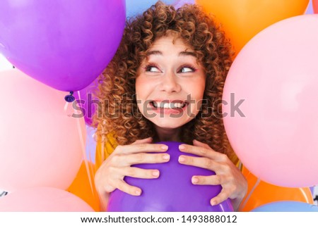 Image closeup of excited delighted woman rejoicing while posing in multicolored air balloons isolated over violet background