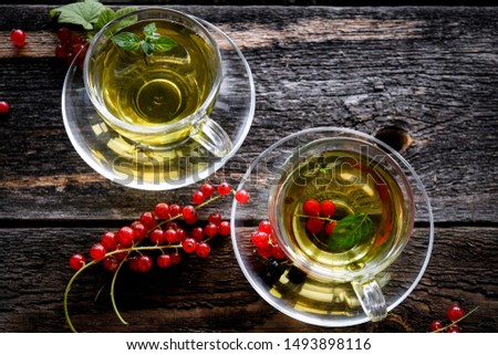 Green herbal tea with a berries in glass cup on wooden table background