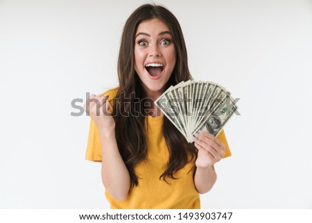 Photo of a surprised excited young girl isolated over white wall background holding money make winner gesture.