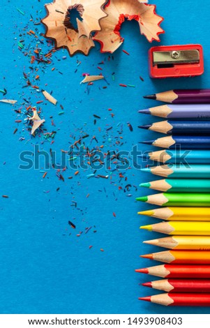 Color pencils and shavings on blue paper background. Copy space.