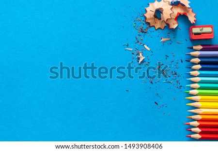 Color pencils and shavings on blue paper background. Copy space.