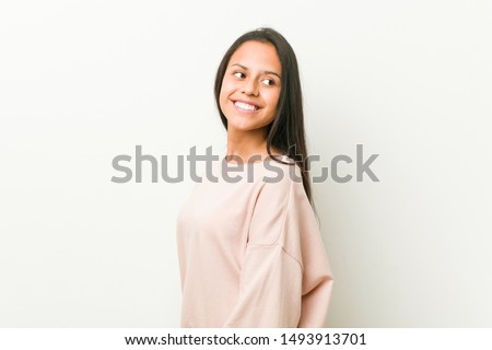 Young cute hispanic teenager woman looks aside smiling, cheerful and pleasant.
