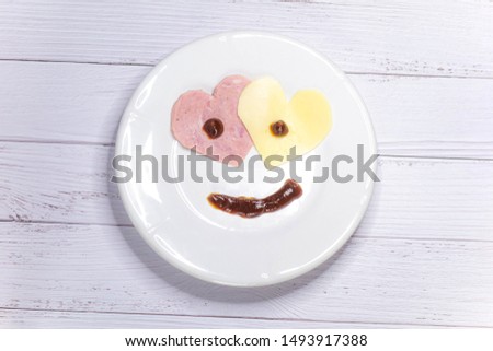 Two hearts made of sausage and cheese. Smile from the food. Food lover. Light background. View from above, flat lay