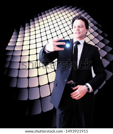 Purposeful attractive man, taking a photo on a smartphone, smiles on a geometric background.