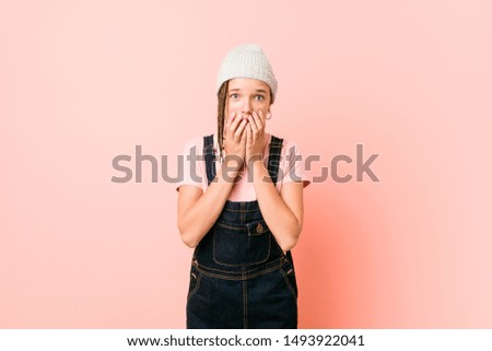 Hispter teenager woman laughing about something, covering mouth with hands.