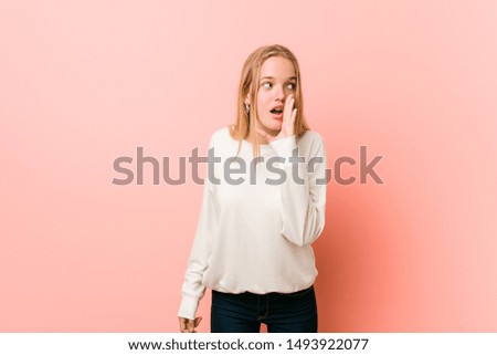 Young blonde teenager woman is saying a secret hot braking news and looking aside