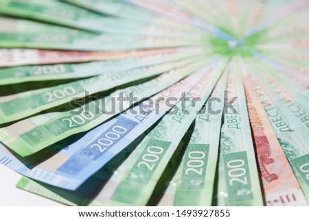 Russian money. 200, 2000 and 5000 ruble paper bills are fan-shaped in a circular pattern. Side view, close up