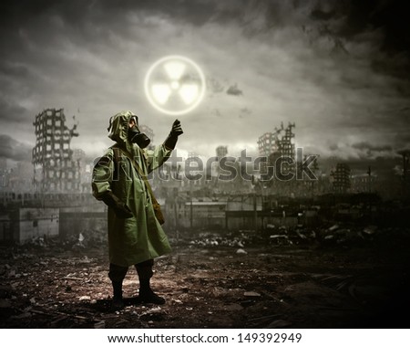Image of man in gas mask and protective uniform touching radioactivity sign
