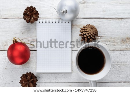 Empty notebook, coffee, fir cone, Christmas ball on a white wooden background
