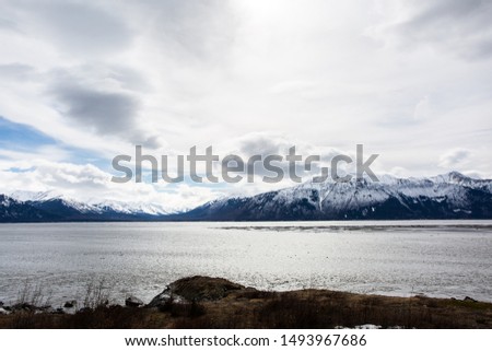 Turnagain Arm Mountain, Alaska - April 11, 2017: A slanted mountain view with the freezing lake. Bright sky on the top of the mountain.