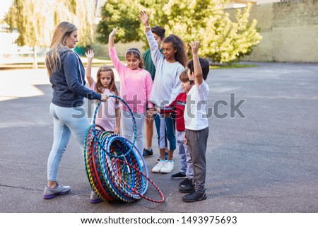 Woman as teacher distributes hoops in physical education to children at summer camp