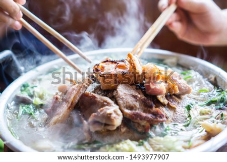 hand holding chopsticks eating Thai barbecue, popular street food  Royalty-Free Stock Photo #1493977907