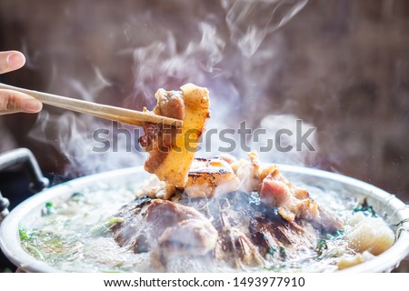 hand holding chopsticks eating Thai barbecue, popular street food  Royalty-Free Stock Photo #1493977910