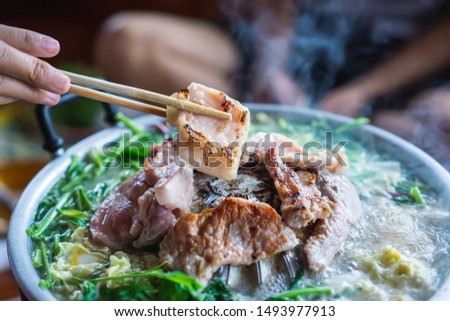 hand holding chopsticks eating Thai barbecue, popular street food  Royalty-Free Stock Photo #1493977913